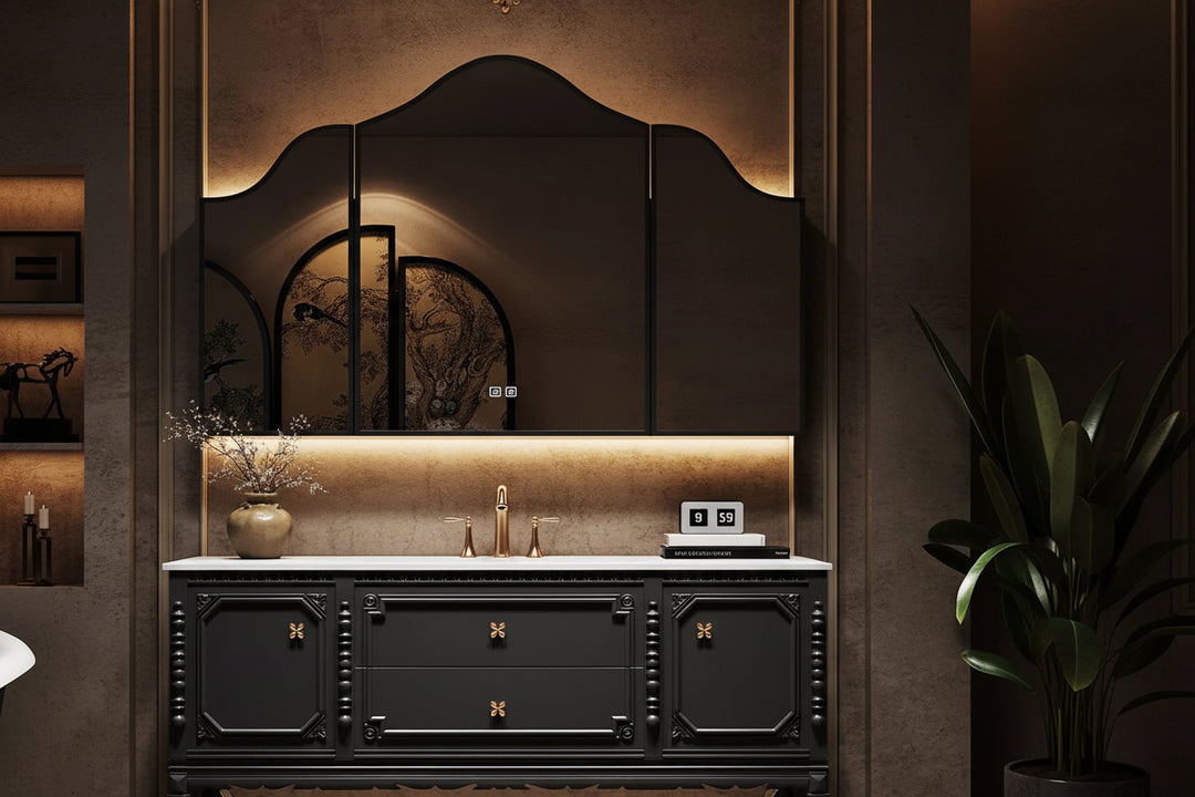 A luxury bathroom vanity set featuring a black wood cabinet with ornate gold hardware, a white marble countertop with an integrated sink, a large arched three-panel mirror, and warm ambient lighting in a dark, elegant bathroom setting.